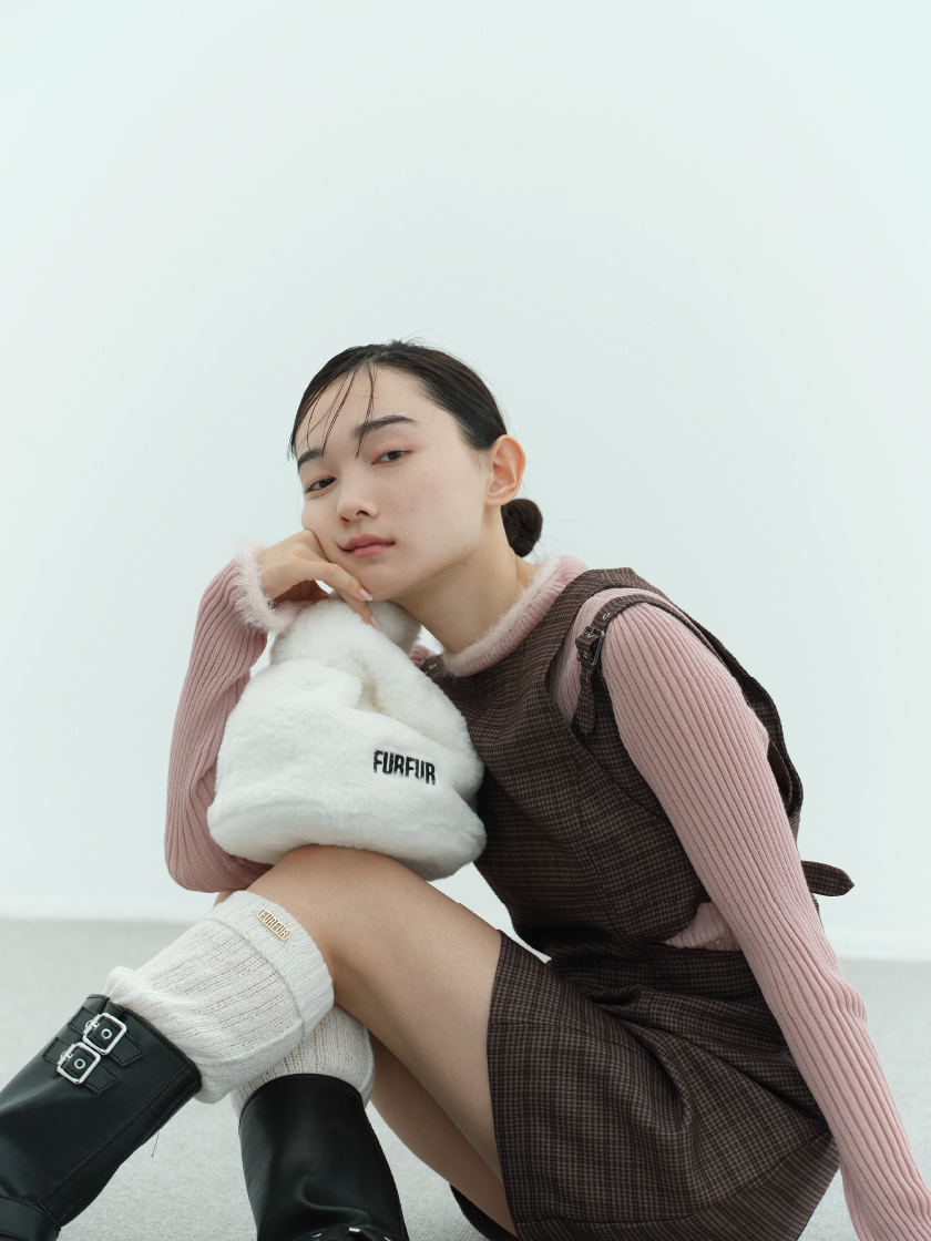 サイドカットミニワンピース・【WEB・一部店舗限定カラー】フェザートリムリブニットトップス・【限定カラー】エコファーマーケットバッグ・レッグウォーマー・バイカーブーツを着用した女性