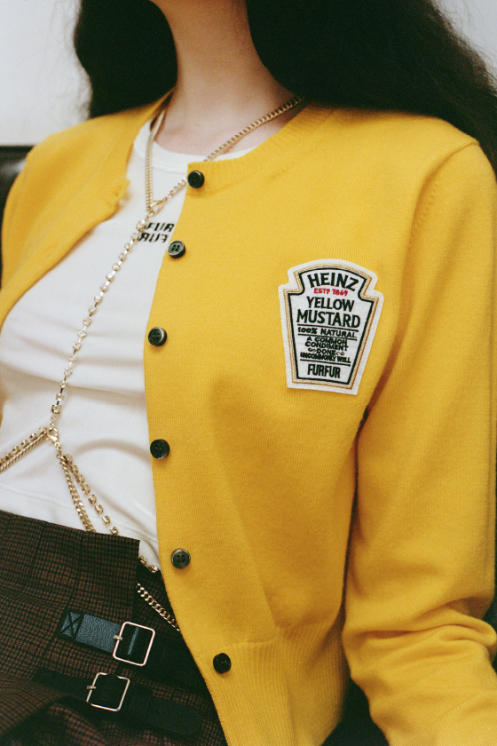 【HEINZコラボ】ワッペンカーディガン・ロゴ刺繍ベロアタンクトップ・プリーツミニスカショーパン・ビジューミックスボディチェーン・バイカーブーツを着用した女性