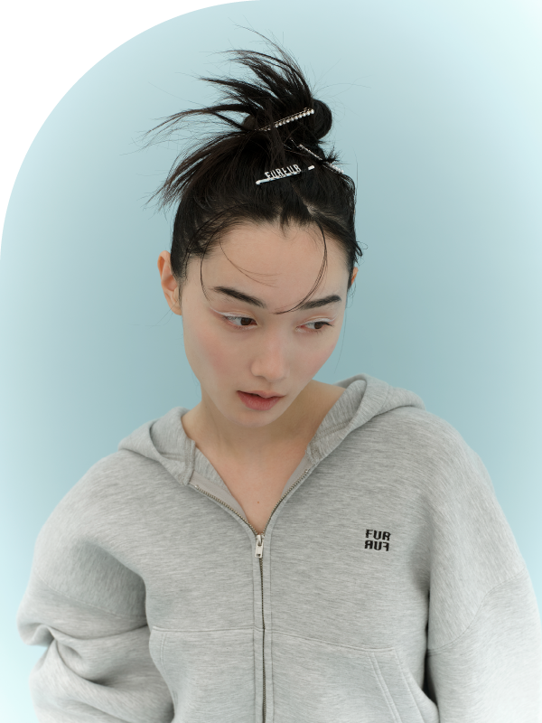 ロゴ刺繍フーディーセットアップ・ロゴヘアピンセット・ラッキーモチーフミックスブレスレット・ダブルストラップバブーシュを着用した女性
