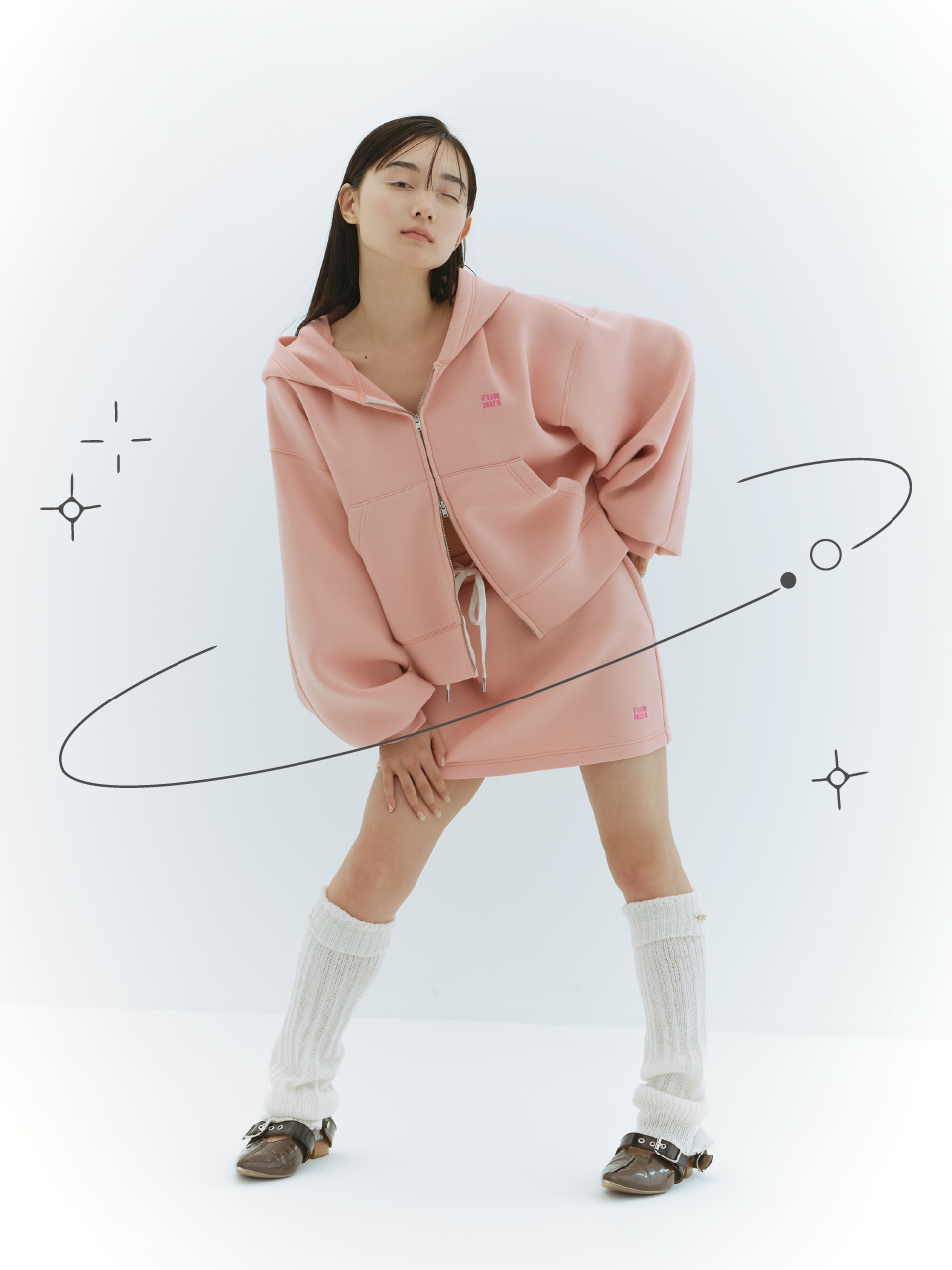 ロゴ刺繍フーディーセットアップ・レッグウォーマー・ダブルストラップバブーシュを着用した女性