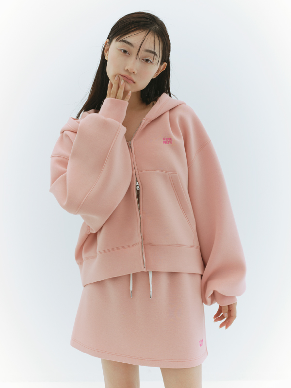 ロゴ刺繍フーディーセットアップ・レッグウォーマー・ダブルストラップバブーシュを着用した女性