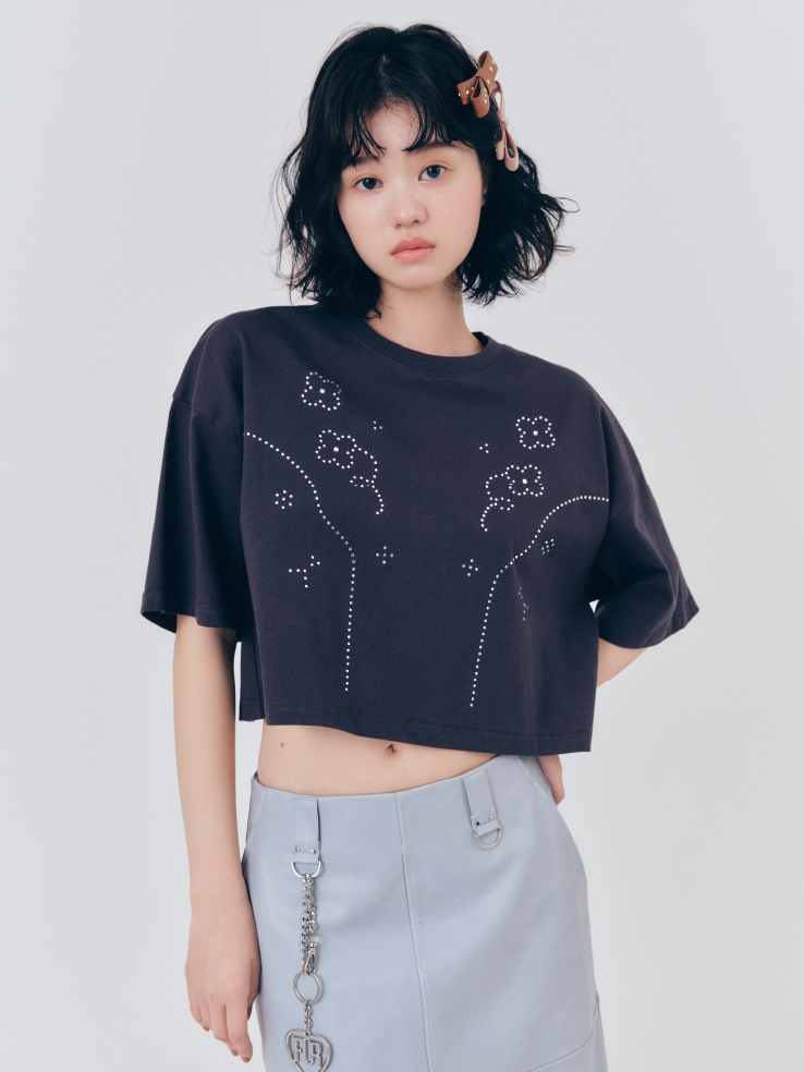 ビジューデザインＴシャツ・レザーライクミディスカート・スタッズリボンヘアクリップ・ハートロゴバッグチャームを着用した女性