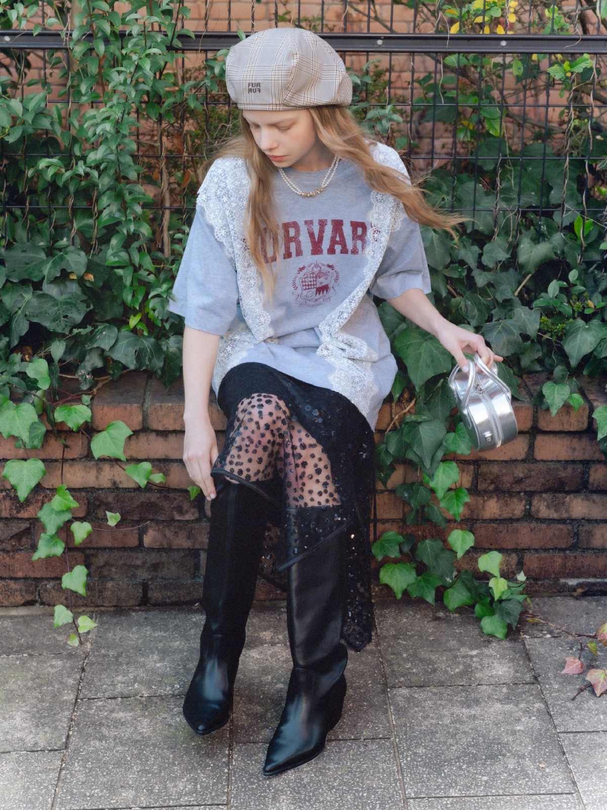 グレーのリメイクデザインレースＴシャツ・黒のスパンコールラップスカート・ブラウンのロゴ刺繍ベレー帽・シルバーのハートショルダーバッグ・ゴールドのフラワーモチーフパールネックレスを合わせたコーディネート