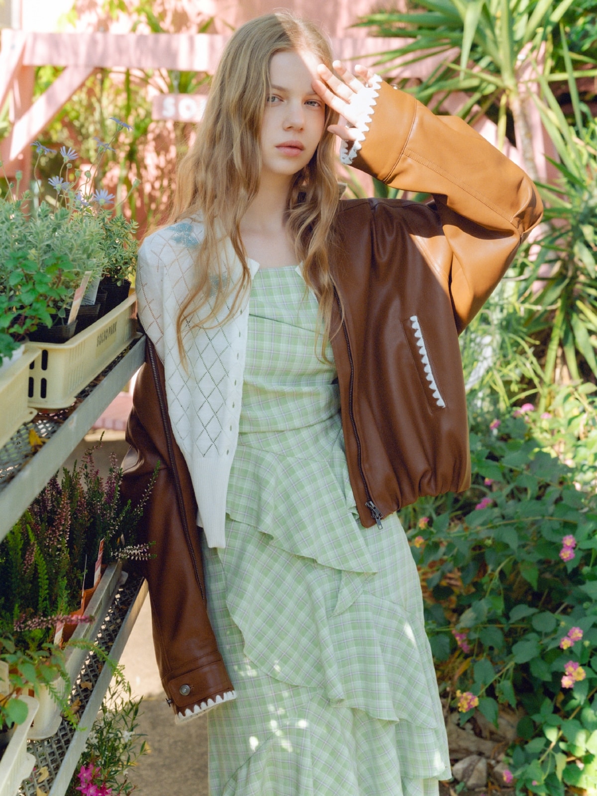 ブラウンのトリミング刺繍レザーライクブルゾン・白のリボンビーズ刺繍アイレットカーディガン・グリーンのアシンメトリーヘムキャミソール・グリーンのアシンメトリーヘムスカート・ブラウンのミニリボンカシメローファーを合わせたコーディネート