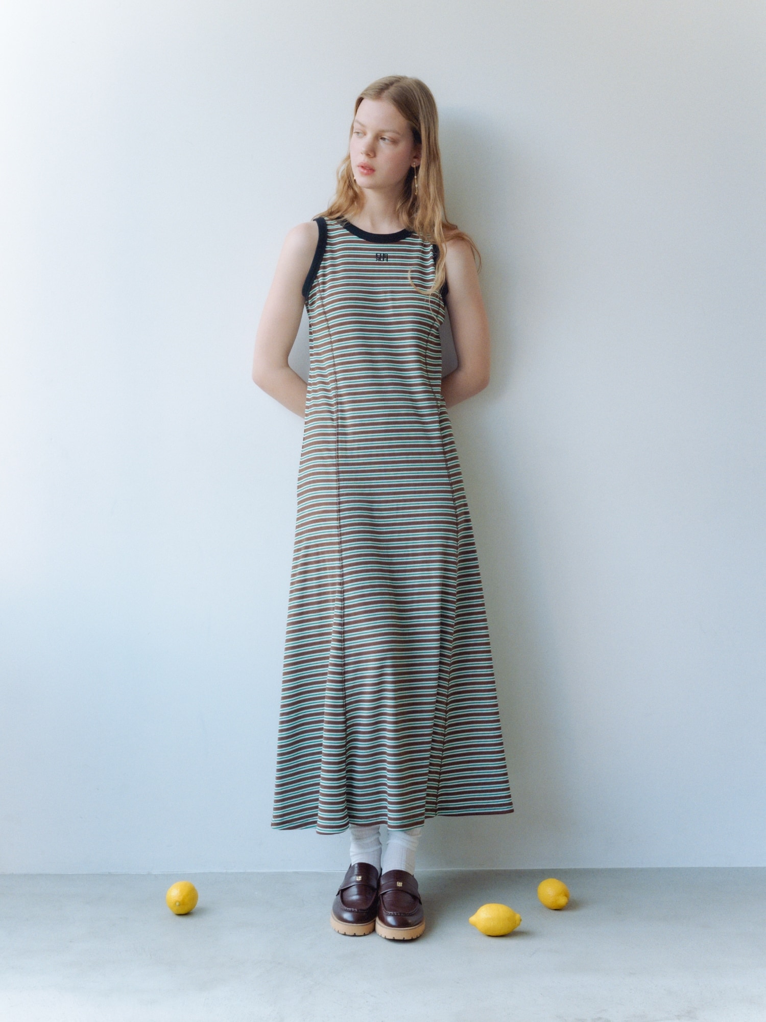 ブラウンのロゴ刺繍ボーダーワンピース・ゴールドのハートモチーフイヤリング・ブラウンのミニリボンカシメローファーを合わせたコーディネート