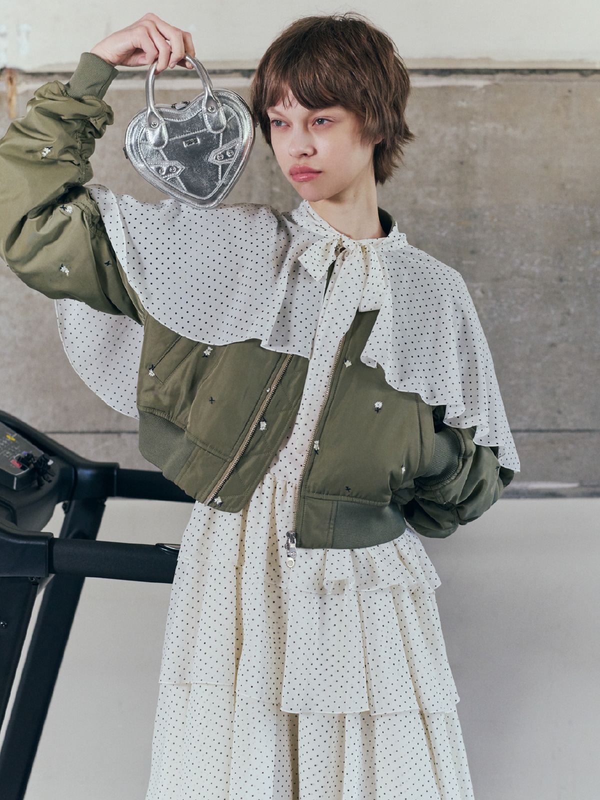 カーキのブルゾンにドットのワンピースを合わせ、シルバーのバッグとブラックのシューズを取り入れたコーディネート。