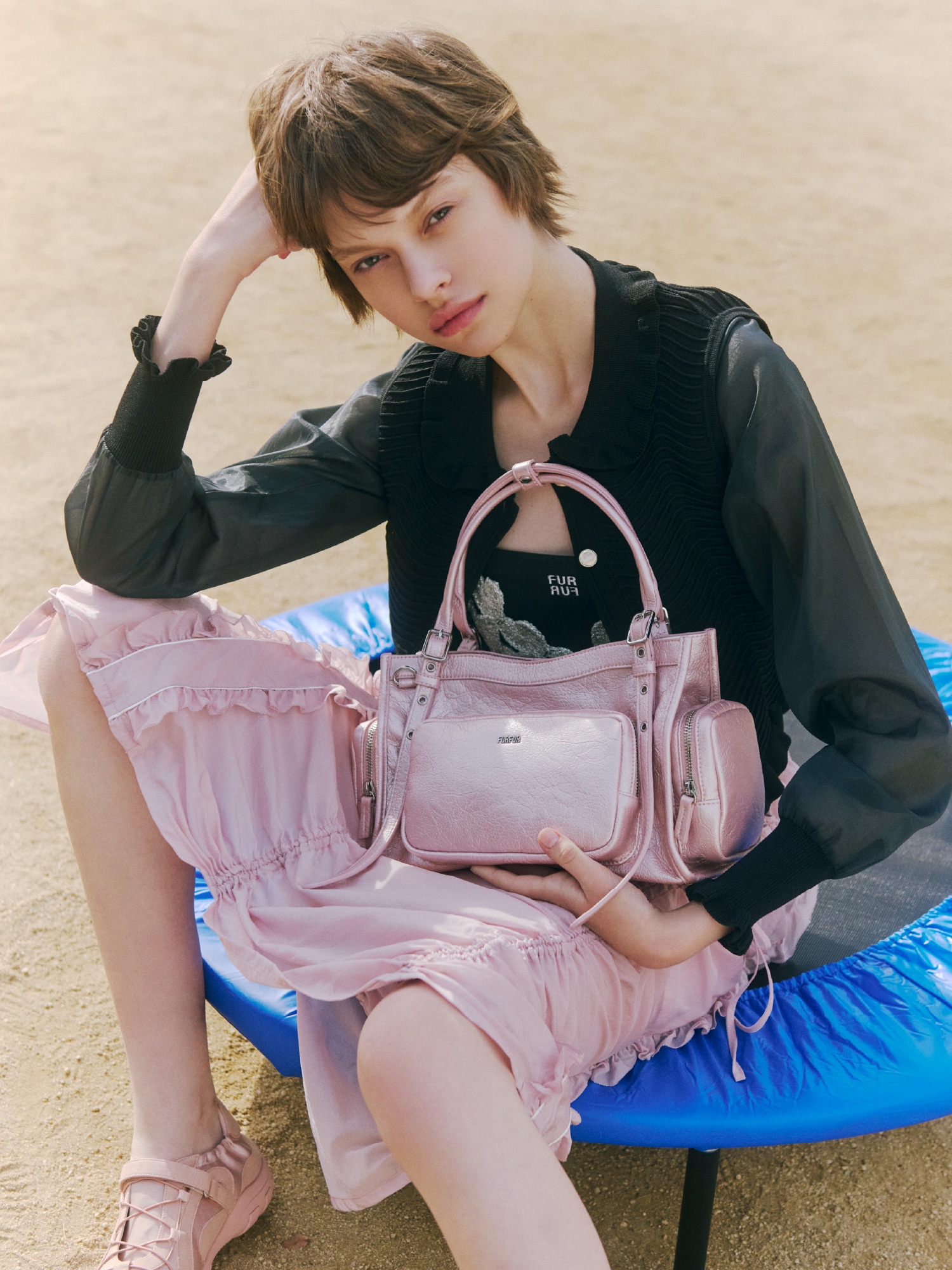 ブラックのカーディガンとシルバーのビスチェ、ブラックのブラトップにピンクのスカートを合わせ、ピンクのバッグとピンクのシューズを取り入れたコーディネート。