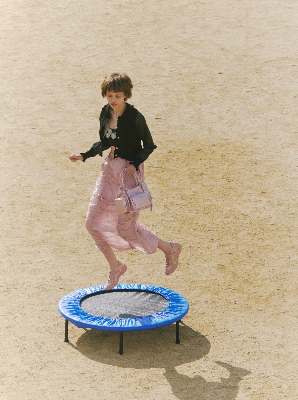 ブラックのカーディガンとシルバーのビスチェ、ブラックのブラトップにピンクのスカートを合わせ、ピンクのバッグとピンクのシューズを取り入れたコーディネート。