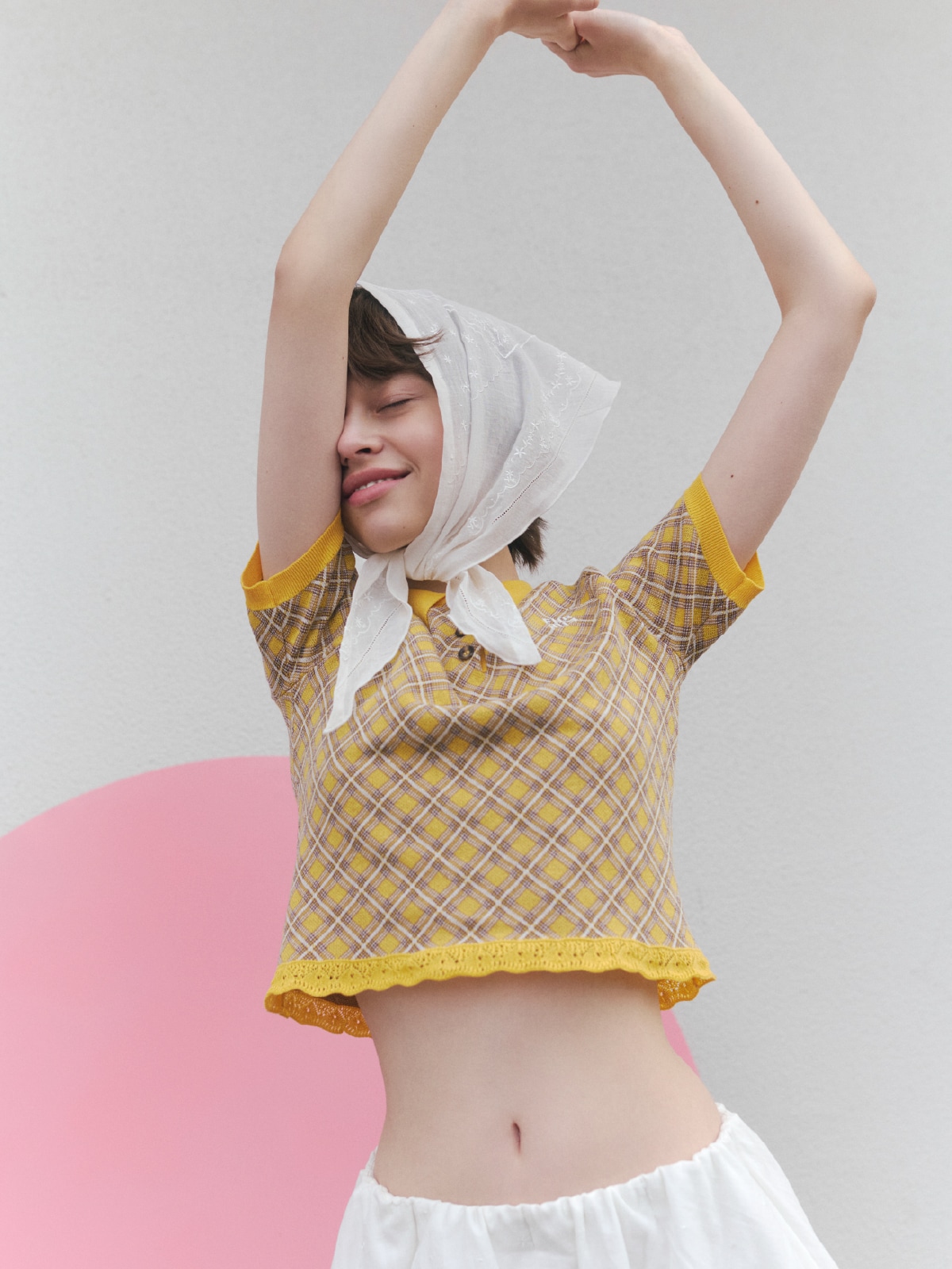 イエローのニットにホワイトのパンツとホワイトのバブーシュカを合わせたコーディネートのバストアップ写真。