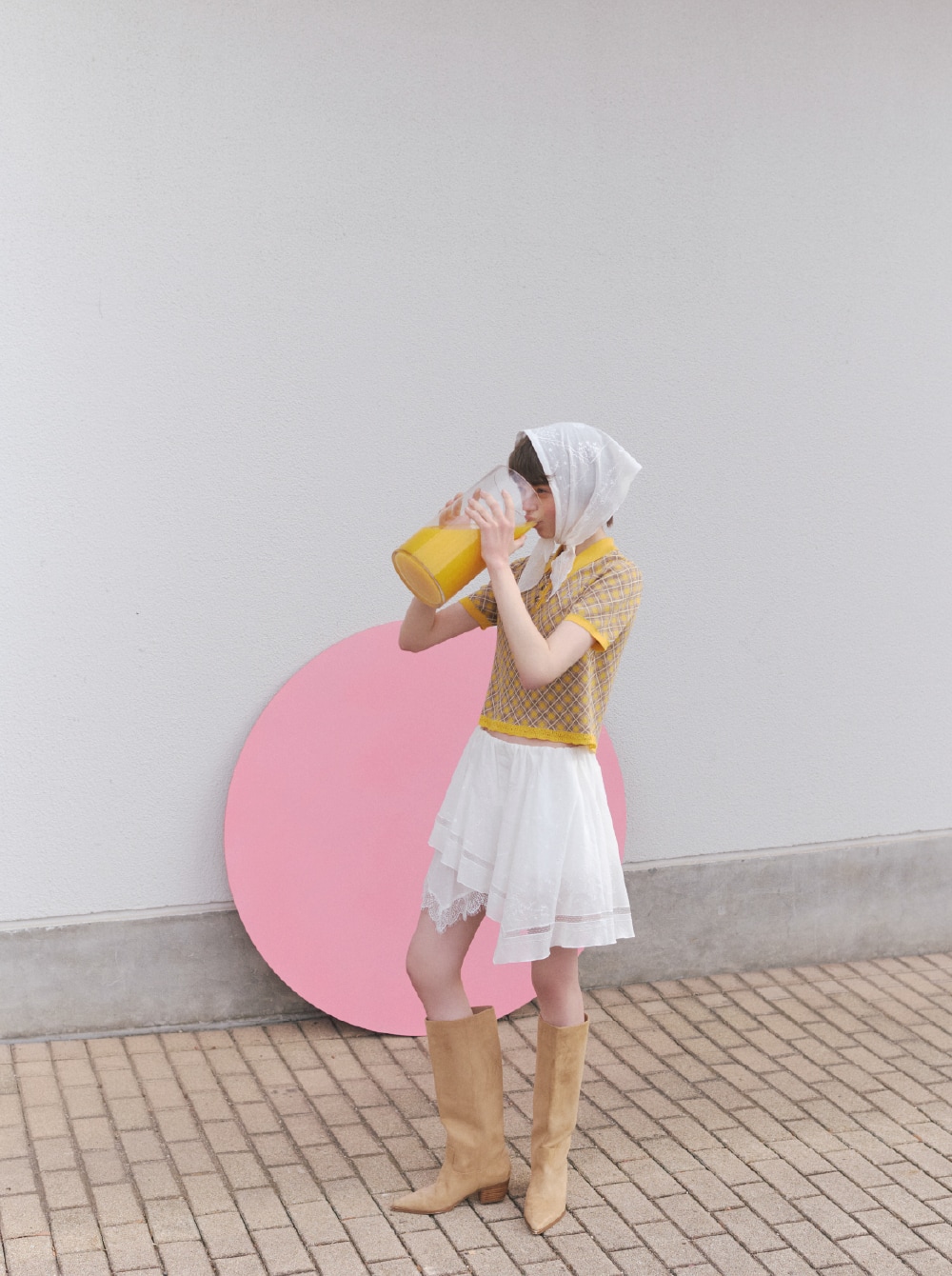 イエローのニットにホワイトのパンツとホワイトのバブーシュカを合わせたコーディネート。