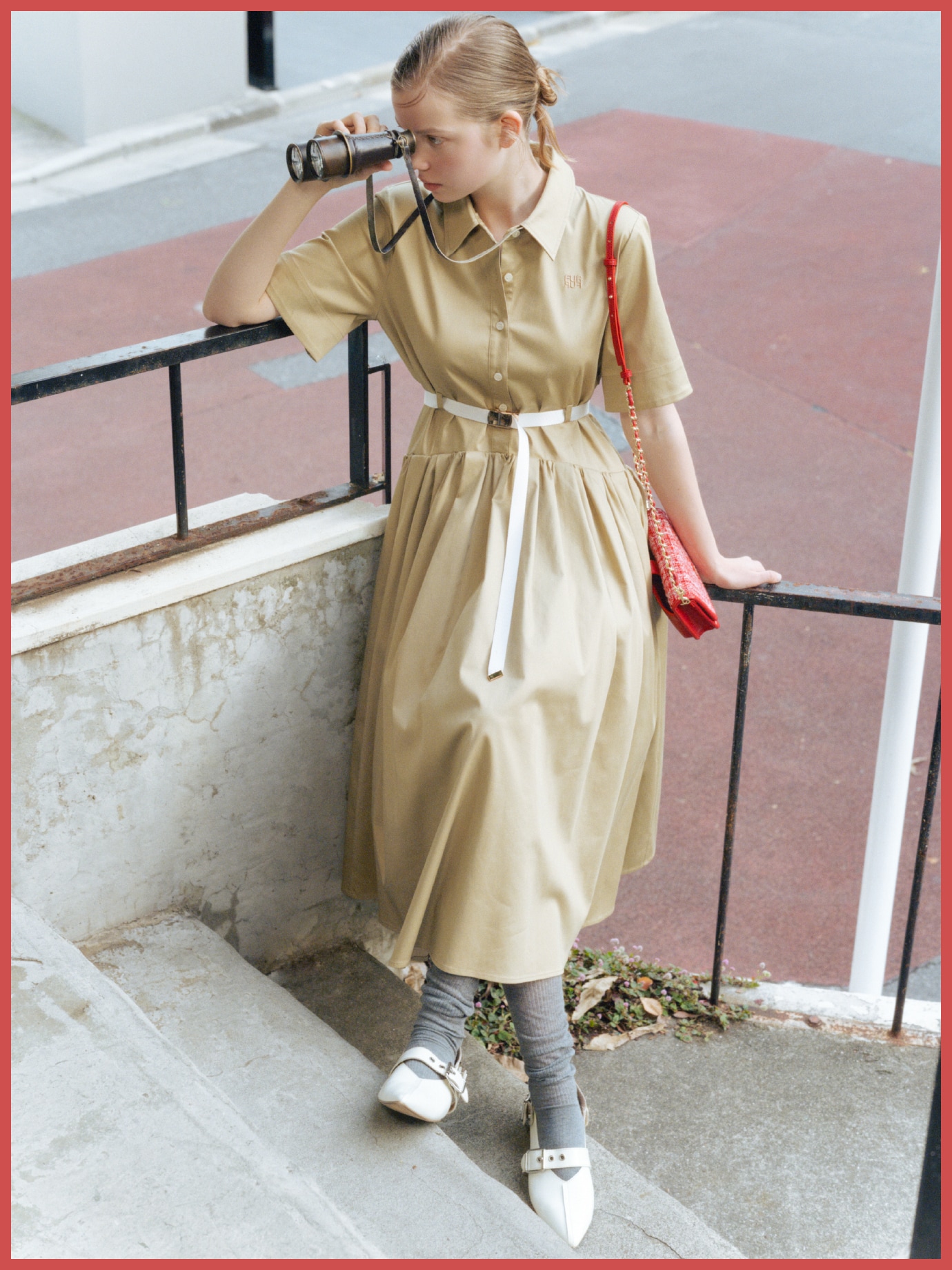 ベージュのベルト付きコードレーンシャツワンピース・赤のツイードロゴフォンホルダー・グレーのロゴシアーリブソックス・白のダブルストラップバブーシュを合わせた、フレッシュな躍動感のあるコーディネート