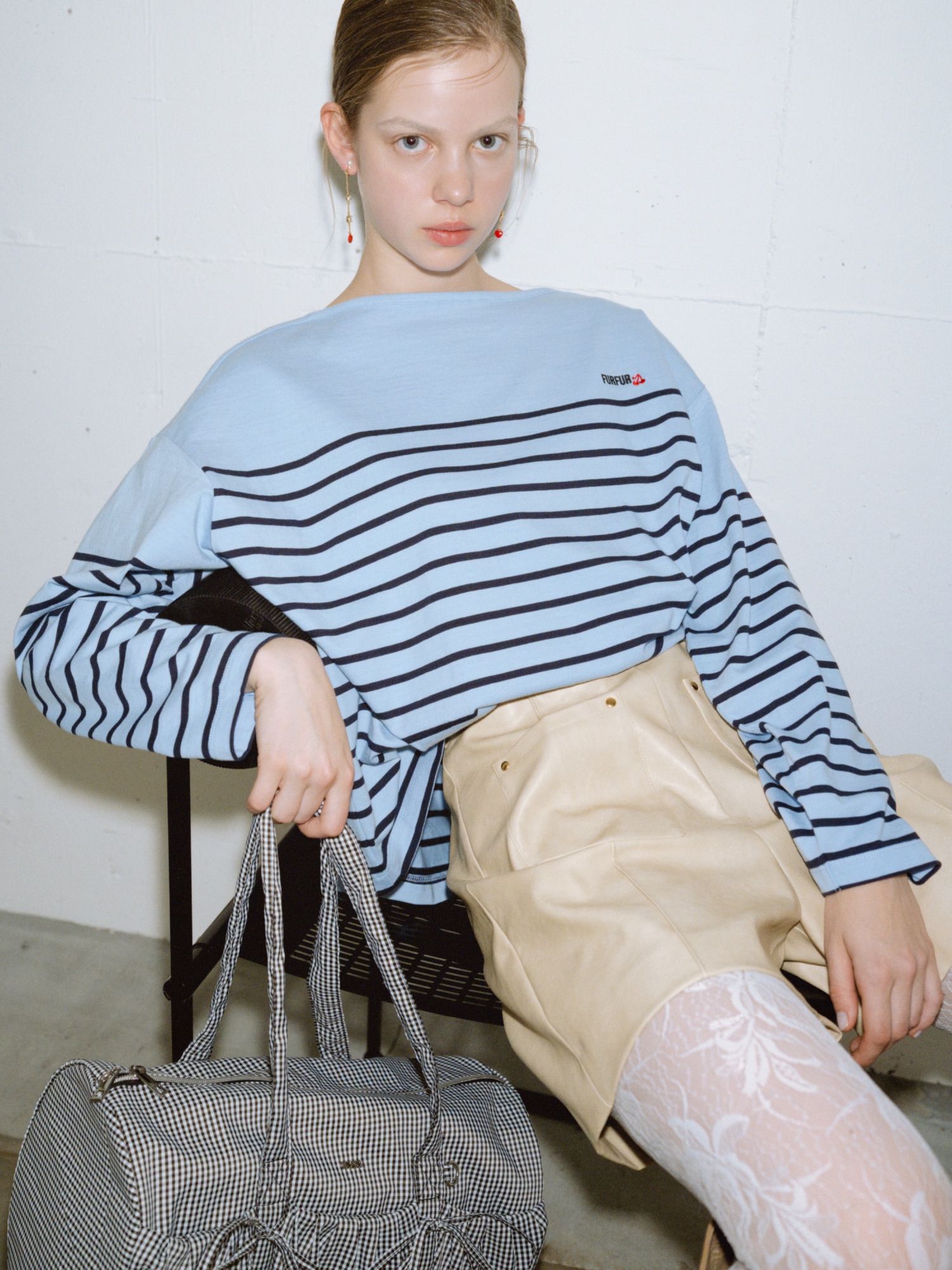 サックスのバスクボーダーロングスリーブＴシャツ・ベージュのレザーライクショートパンツ・赤のハートモチーフイヤリング・黒のリボンドラムバッグを合わせた、ガーリーな要素を大人っぽく取り入れたコーディネート