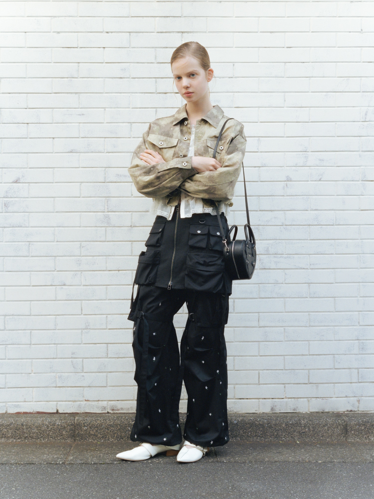 ミックスの刺繍クロップドシャツジャケット・オフホワイトのレースフリルブラウス・黒のカーゴミニスカートとフラワー刺繍カーゴパンツとハートショルダーバッグ・白のダブルストラップバブーシュを合わせた、ストリート感と上品さをミックスしたコーディネート