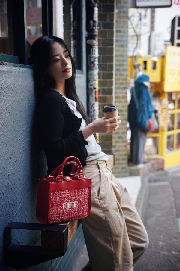 赤のツイードロゴトートバッグ・黒のフリルカーディガンを合わせたコーディネート