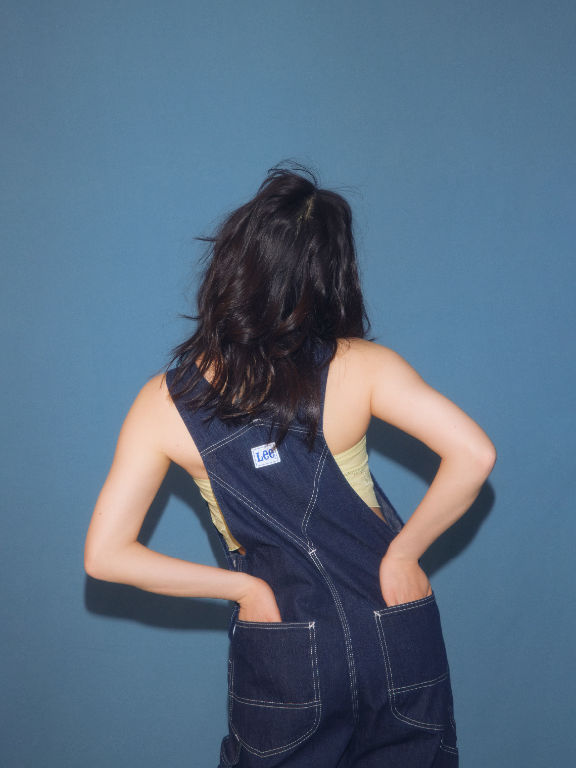 ハンカチ刺繍マルチウェイキャミソール・Ｌｅｅコラボデニムオーバーオール・スカーフバンダナを着用した女性の後ろ姿
