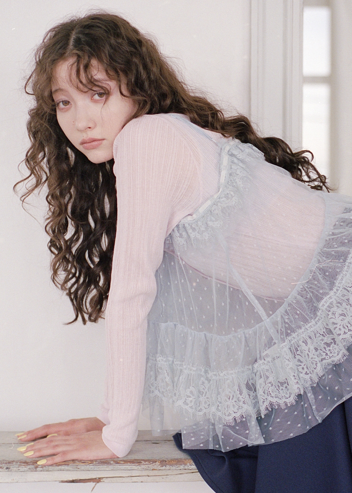 ピンクのフリルペプラムカーディガン・サックスのキャミソール・ネイビーのフレアミニスカート・ブルーのネックレス・シルバーのスニーカーを合わせたコーディネート