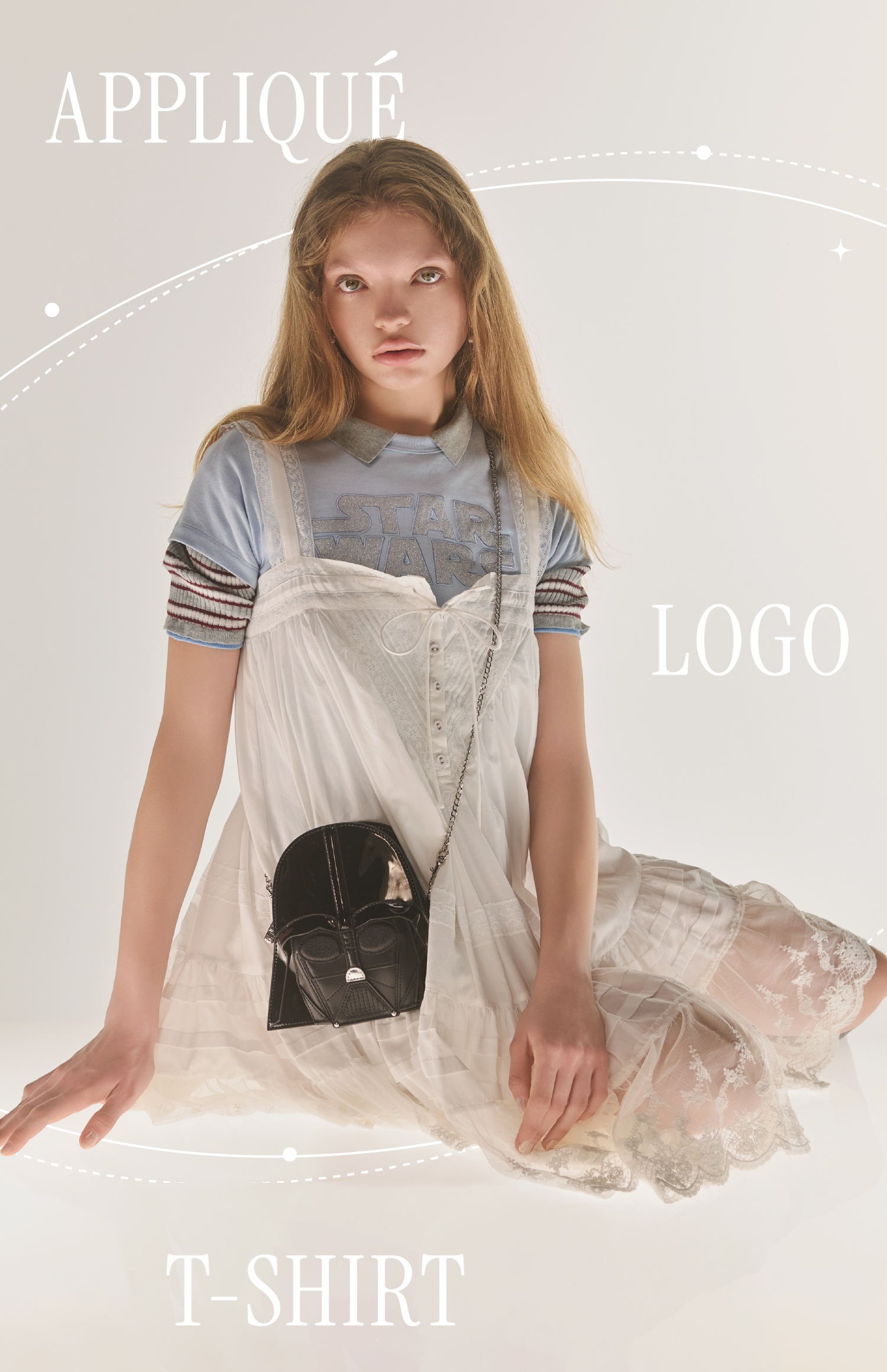 サックスのアップリケロゴTシャツ・ダース・ベイダーモチーフバッグ・グレーのカラーブロックニットポロシャツ・白のレースデザインチュニックワンピース・イヤリングを合わせたコーディネート