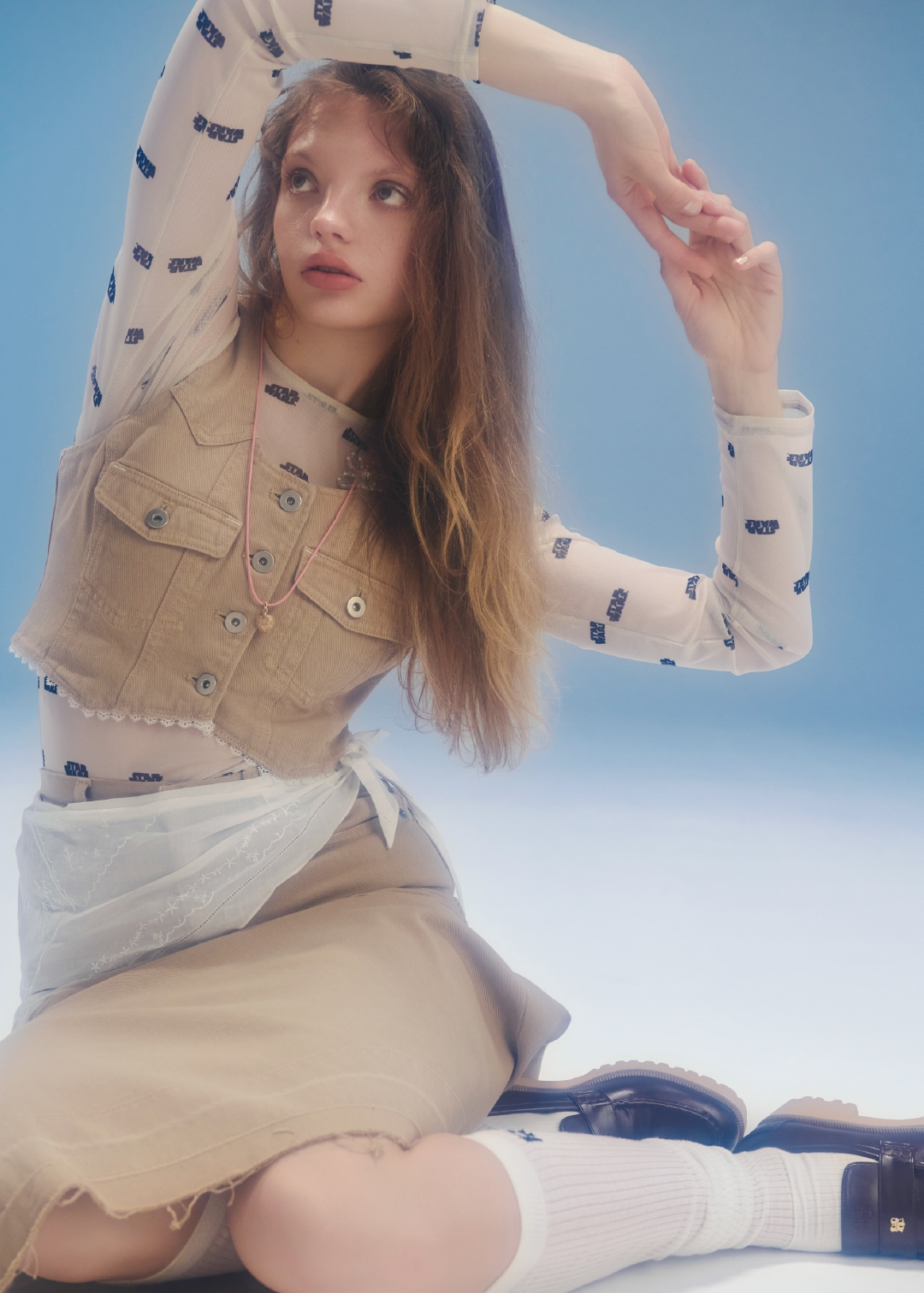 アイボリーのロゴシアープルオーバー・ベージュのレースドッキングデニムベストとレースドッキングデニムスカート・白のハンカチ刺繍マルチウェイキャミソール・ネックレス・ソックス・ブラウンのミニリボンカシメローファーを合わせたコーディネート