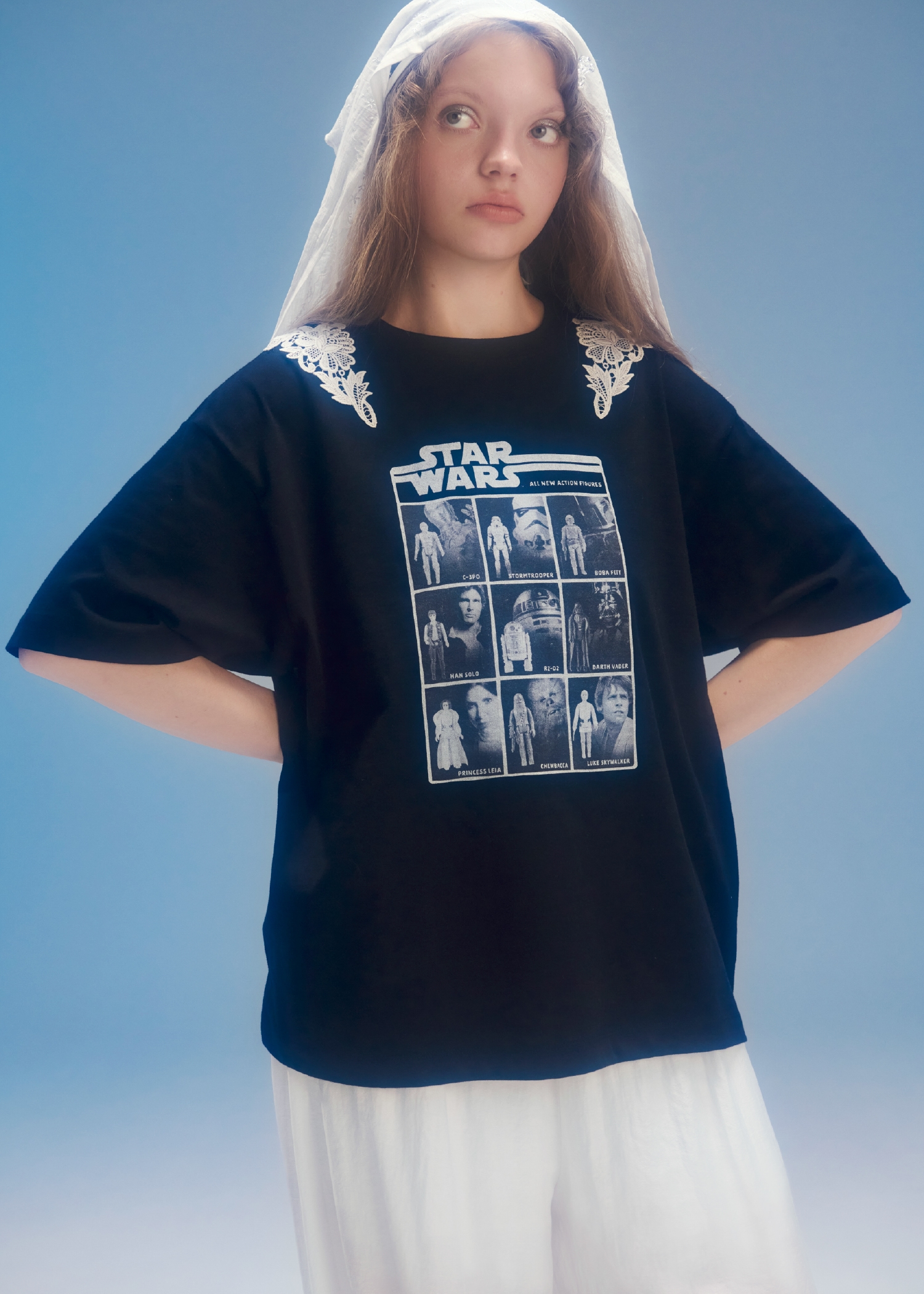 黒のグラフィックプリントレースTシャツ・チャーム・白のレーストリムドロストパンツとハンカチ刺繍マルチウェイキャミソール・ピンクのバッグとクロスストラップリボンパンプスを合わせたコーディネート