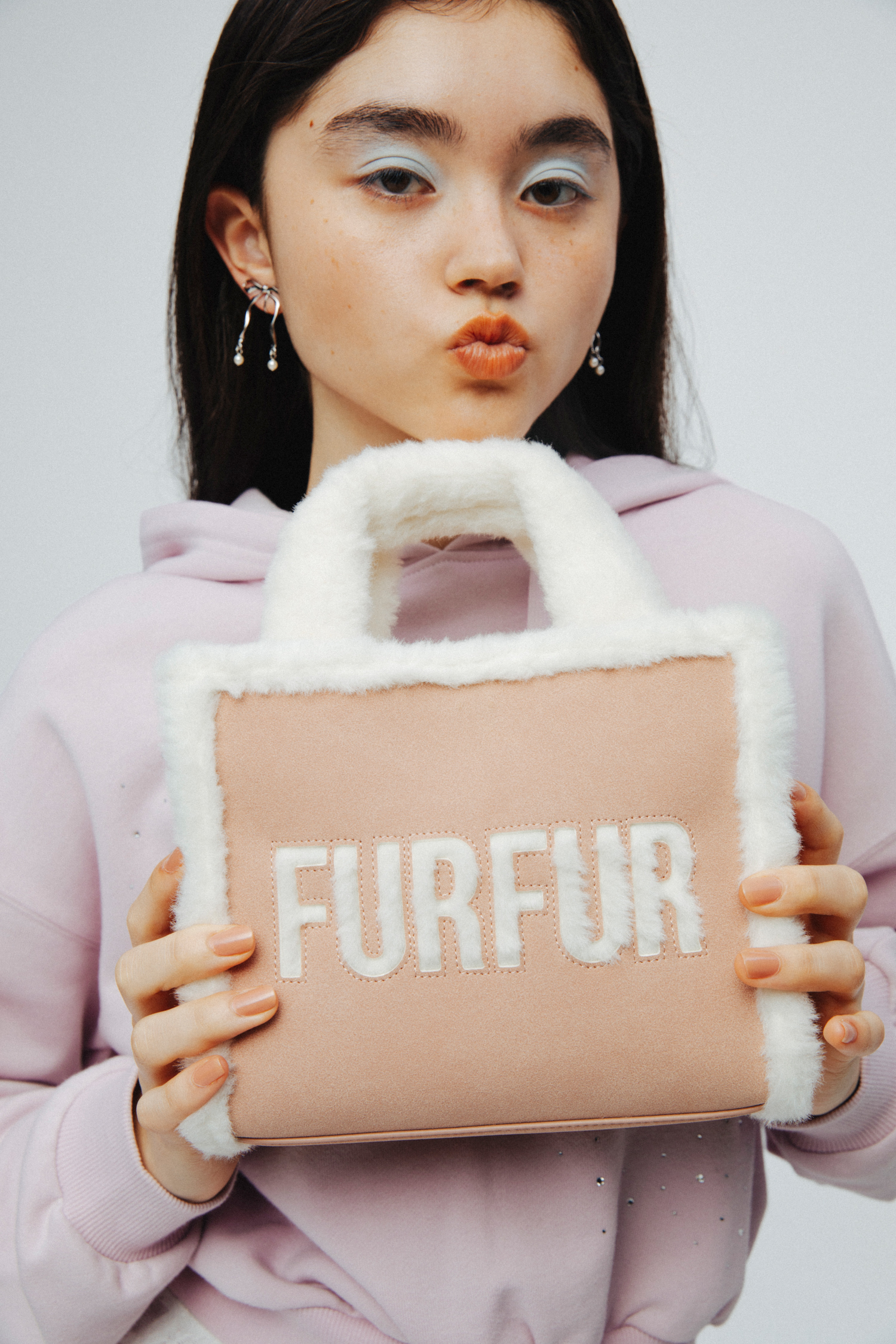 ビジュークロップドフーディー・ビジュースウェットパンツ・【WEB・一部店舗限定カラー】ムートンロゴトートバッグ・スウィングリボンイヤリング・レース付け襟・ダブルストラップバブーシュを着用した女性