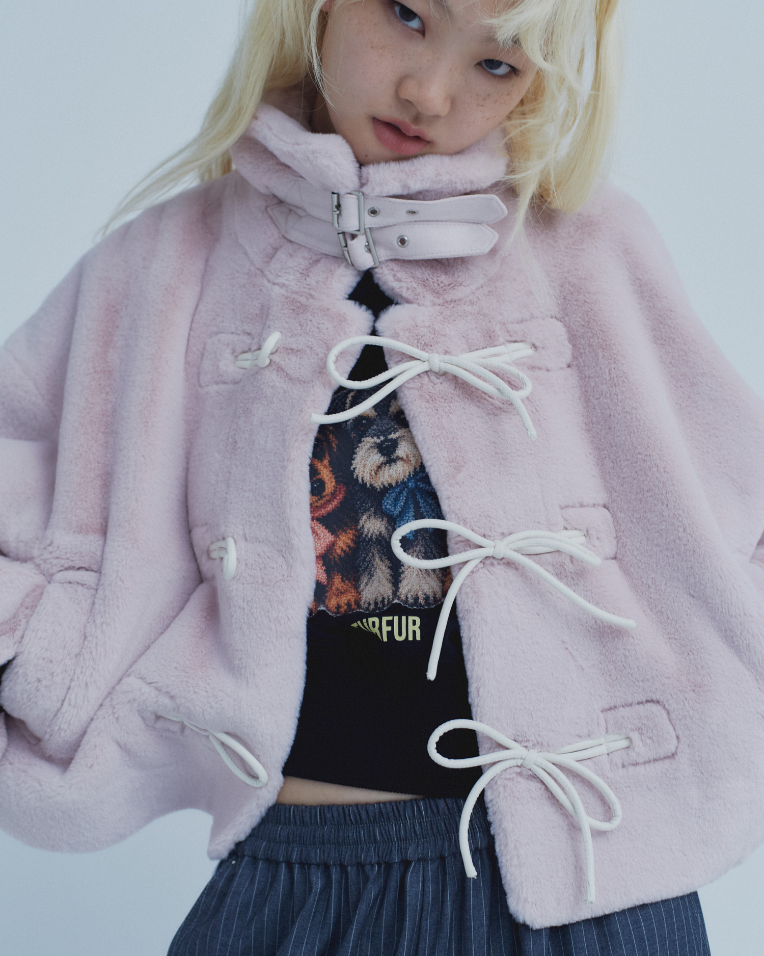 ピンクのボアジャケットのリボン留めとプリントTシャツを寄りで見せたカット